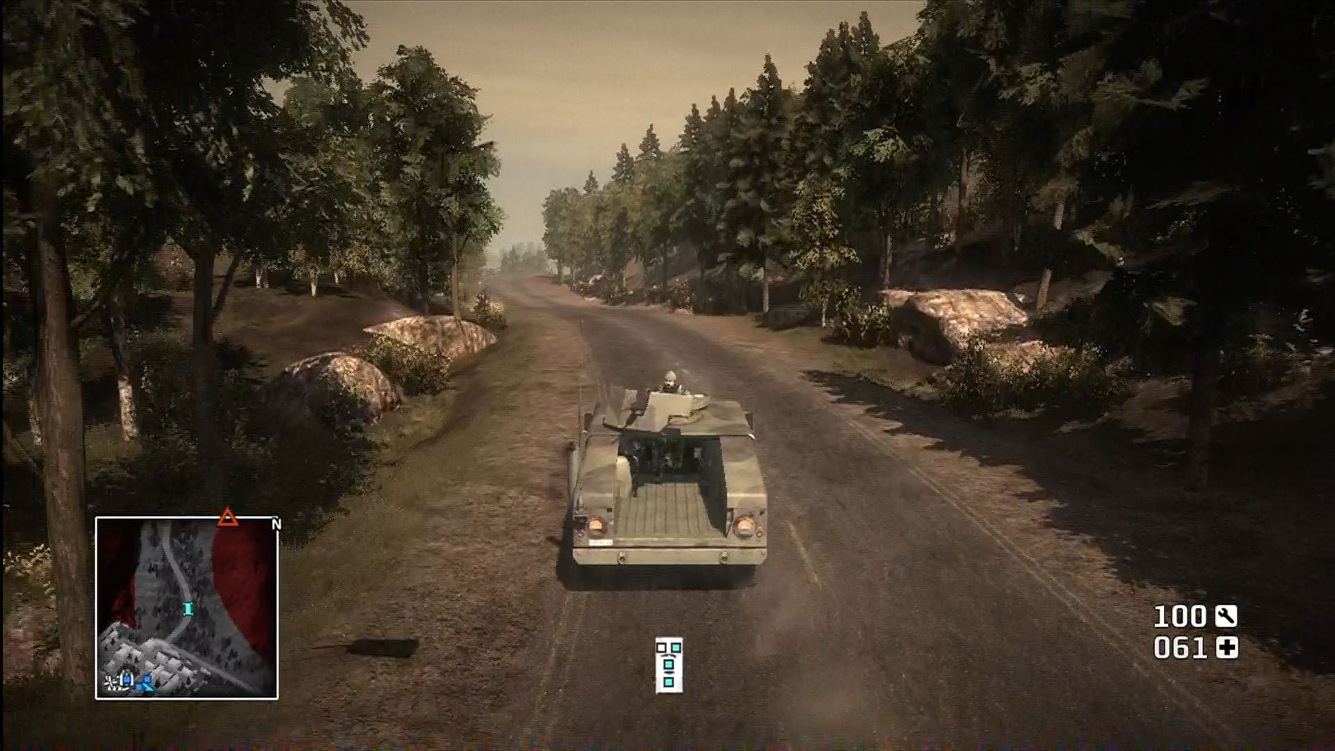 Military vehicle driving down road in foresty terrain.
